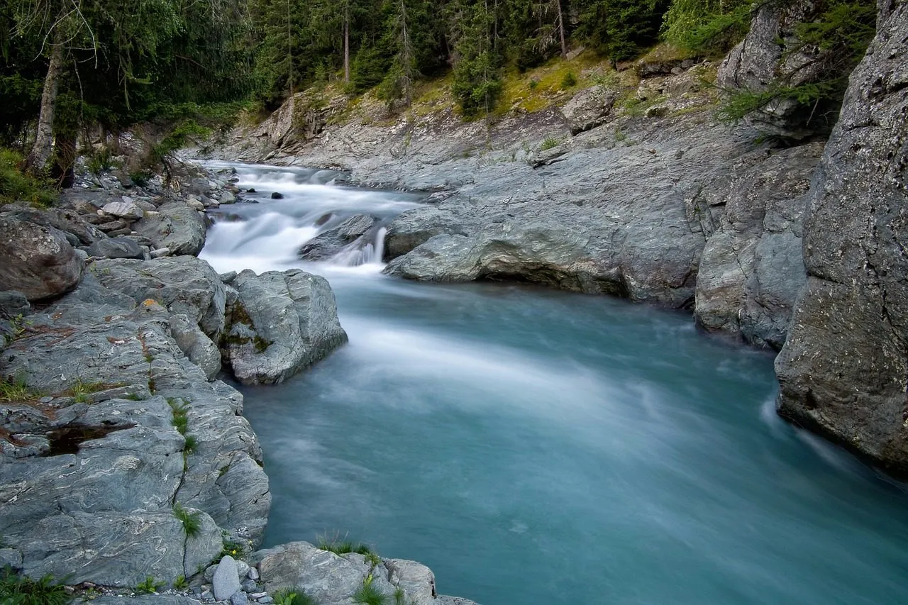 A clear blue mountain river running between smooth granite boulders